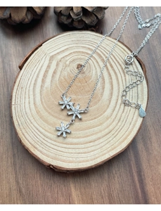 Detail view of triple snowflake pendant necklace with white zircons on wooden background