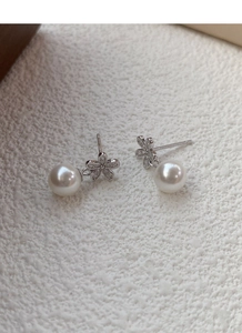 Dettaglio di orecchini a fiore in argento S925 con perle bianche e diamanti scintillanti