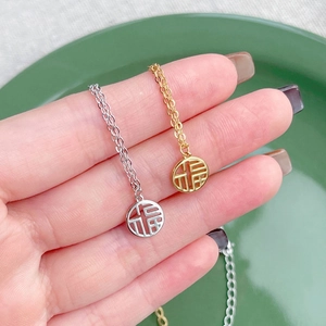 Hand holding S925 sterling silver Fu character pendant necklaces in gold and silver