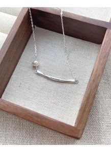 Macro shot of S925 silver necklace with Freedom engraved bar and freshwater pearl