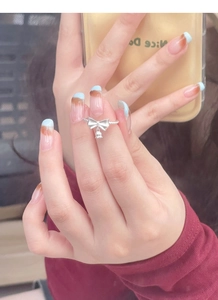Detailed view of S925 sterling silver bow ring with small bell pendant on hand
