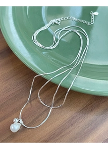 Dettaglio della catena d'argento a doppio strato con perla barocca su piatto in ceramica