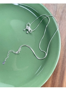 Gros plan d'un collier nœud en argent S925 sur une chaîne serpent en céramique