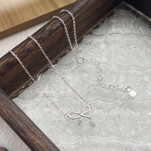 Élégant collier nœud en argent S925 avec pendentif en zircon sur plateau en bois vintage