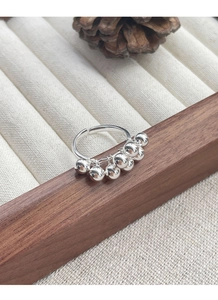 Detailed close-up of a silver bead cluster ring on a natural wooden display stand