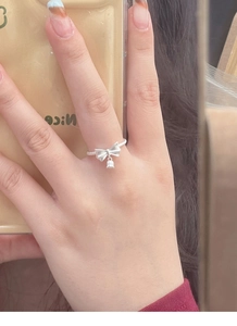 Detailed view of an S925 silver bow ring with a bell charm and twisted band