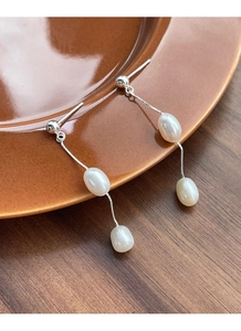Détail de boucles d'oreilles en perles baroques argentées suspendues à un plateau en céramique