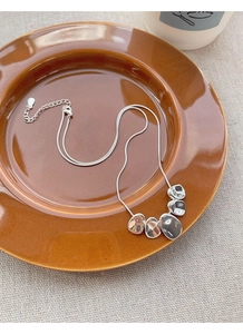 Close-up of S925 sterling silver snake chain with irregular pebble pendants on ceramic plate