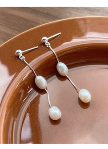 Détail de boucles d'oreilles chaîne en argent S925 avec perles d'eau douce sur céramique