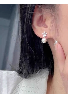 Dettaglio di orecchini a fiore in argento con diamanti e perla bianca a goccia
