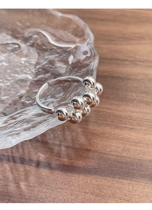 Detailed shot of S925 sterling silver ring with ball cluster design on glass surface