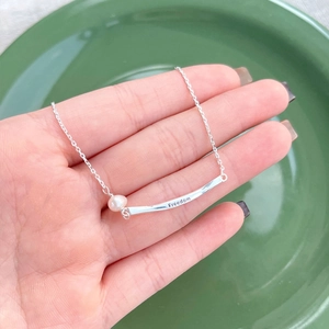 Minimalist S925 silver necklace with Freedom bar and freshwater pearl on green background