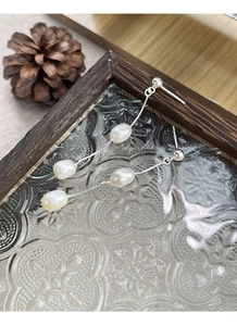 Détail de boucles d'oreilles longues en argent S925 avec perles d'eau douce sur plateau