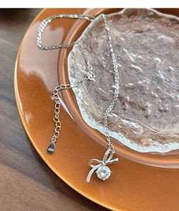 Vue détaillée d'un collier nœud en argent S925 avec zircon brillant sur un plat en céramique