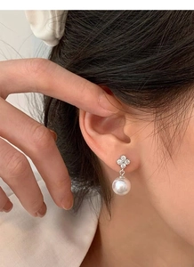 Détails des boucles d'oreilles trèfle en argent avec cristaux et perles sur le mannequin