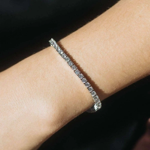 Gros plan d'un bracelet de tennis argenté serti de zircons 5A sur un poignet féminin