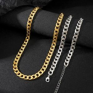 Dettaglio di catene cubane oro e argento con chiusura a moschettone su sfondo scuro