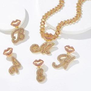 Close-up of hip hop gold necklaces with iced out pink lip charms and crystal initial pendants