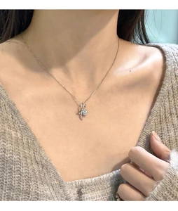 Gros plan du collier nœud en or rose avec diamants étincelants sur un pull