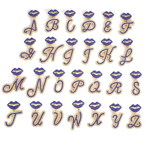 Macro view of iced out A-Z alphabet pendants with blue rhinestones and lip bail