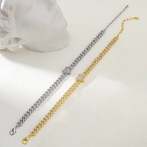 Dettaglio dei ciondoli a cuore su bracciali a maglia cubana color oro e argento