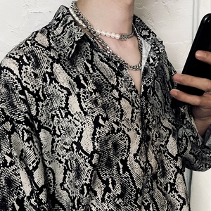 Dettaglio camicia con stampa serpente bianco e nero e collana a catena lucida