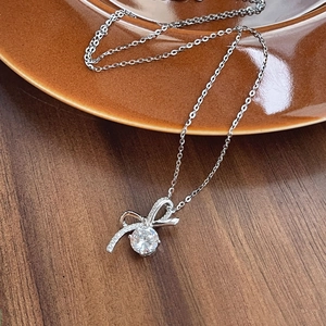 Collier nœud en argent S925 avec pendentif diamant rond sur un fond en bois sombre