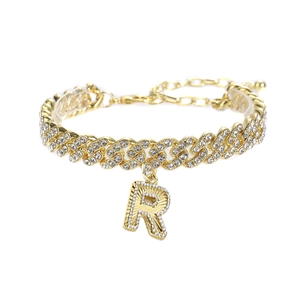 Détail macro d'une chevillère gourmette dorée avec un pendentif lettre R serti de strass