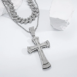 Macro shot of iced out silver cross pendant with angel wings on white stone background