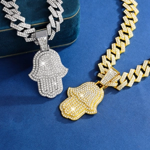 Détail des pendentifs Main de Fatma en or et argent sertis de cristaux avec chaîne cubaine