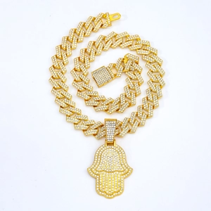 Détail de chaîne à mailles cubaines dorées avec pendentif main de Hamsa serti de strass