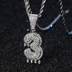 Gros plan sur le pendentif hip-hop argenté numéro 3 serti de strass avec effet goutte