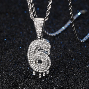 Gros plan sur un pendentif hip hop chiffre 6 argenté avec strass et effet goutte