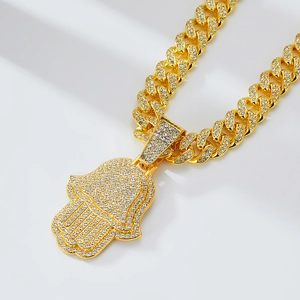Détail du pendentif Main de Fatma doré avec diamants sur une chaîne à maillons cubains chic
