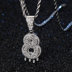 Gros plan du pendentif hip hop chiffre 8 avec strass et breloques en gouttes d'eau