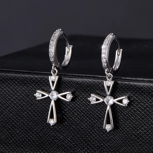 Détail de boucles d'oreilles croix en argent serties de zircons sur fond de cuir noir