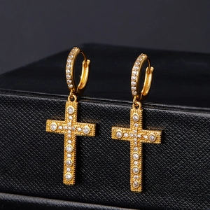 Close-up of gold cross earrings featuring micro-paved cubic zirconia on a jewelry box