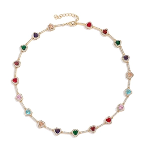 Detalle macro de un collar de circonitas de colores en forma de corazón con cadena bañada en oro