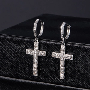 Macro shot of micro-paved zircon cross earrings on a black leather jewelry box texture