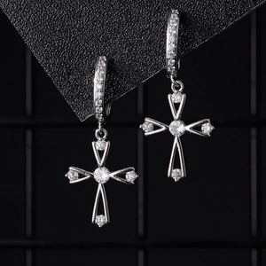 Détail macro de boucles d'oreilles croix en argent serties de zircons étincelants