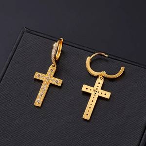 Detailed close-up of golden cross earrings with zircon pavé setting on black leather