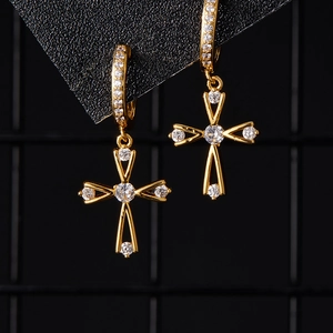 Détail de boucles d'oreilles croix dorées avec zircons et créoles à charnière