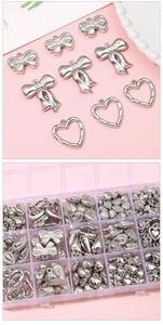 Close-up of silver heart and bow pendants for DIY jewelry making in a plastic organizer