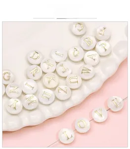 Macro detail of white shell letter beads with gold engraving for DIY jewelry crafting