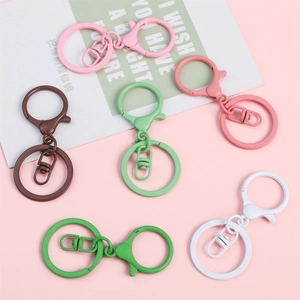 Colorful matte candy paint metal keychain set in various pastel colors on a pink backdrop