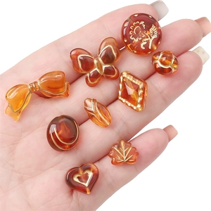 Hand holding vintage amber acrylic beads with gold foil details for DIY jewelry making