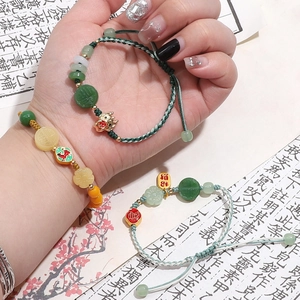 Detail of hand-woven bracelet with jade-like beads and Chinese lucky charms