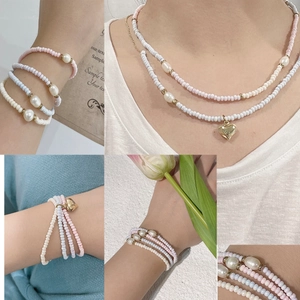 Meerlaagse kralenketting en armband met pastelhars parels en gouden hartvormige hanger