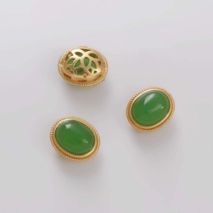 Detalle de cuentas de piedra verde ovaladas con marco dorado y patrones florales calados