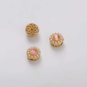 Primer plano de cuentas espaciadoras de cobre dorado con opalo rosa y detalles de perlas